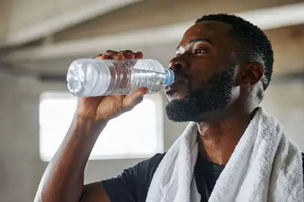 Image of man drinking water to improve hydration Hemel Hempstead after work out.